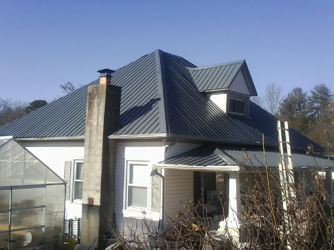 Dark blue standing seam metal roof on a white farmhouse with dormer — Slate & Tile Roof Repair by Roofing Brothers in Bearsville