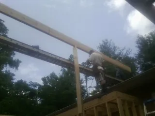 Carpenter setting a ridge beam over a new addition frame — Ice Dam Removal by Roofing Brothers in Bearsville