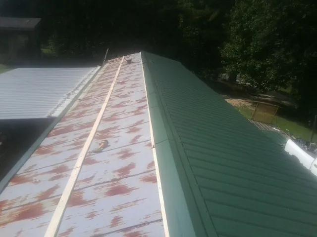 Old rusted panels beside newly installed green metal roofing — Wind Damage Roof Repair by Roofing Brothers in Bearsville