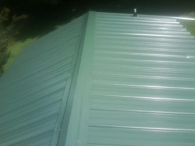 New green metal panels meeting at the ridge of a roof — Flat Roof Repair work by our crew in Bearsville