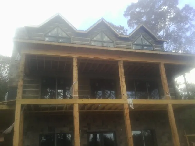 Dormers and porch framing on a large log home under construction — Roof Coating work by our crew in Bearsville