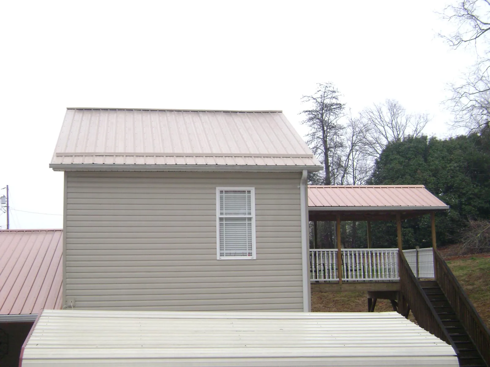 Tan metal roofs on a two story addition and attached porch, from a Roof Replacement job in Bearsville