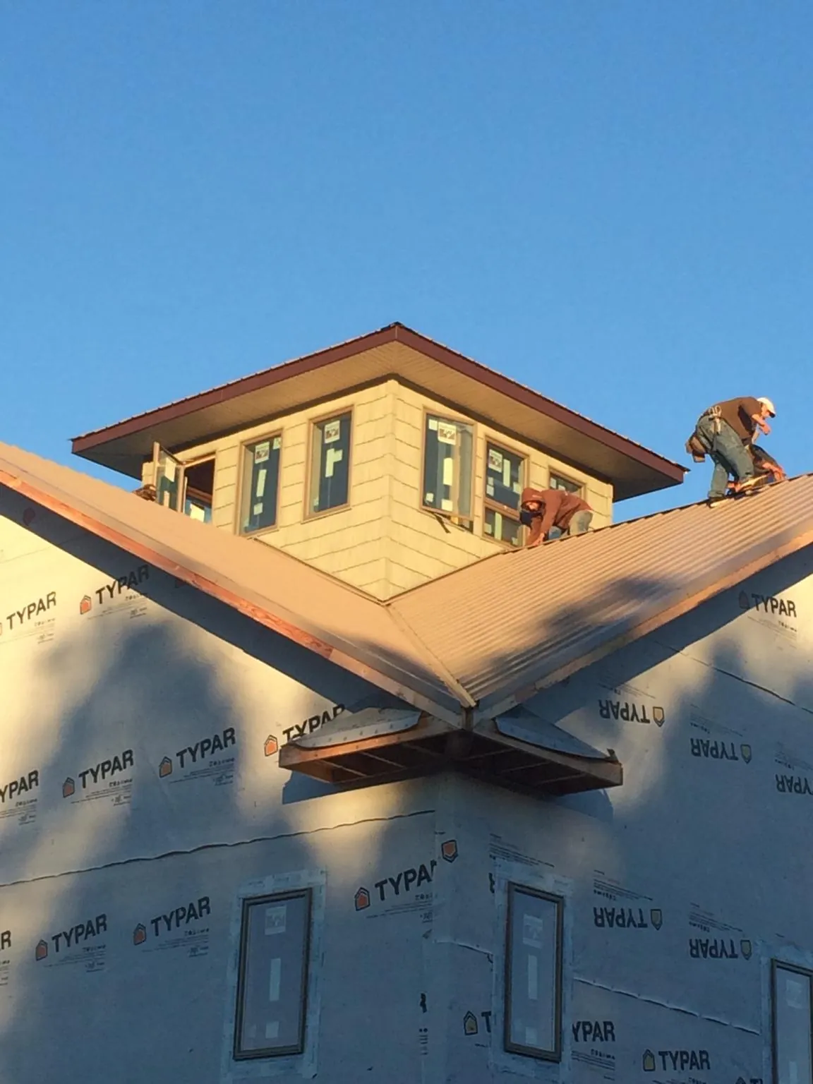 Roofers working around a rooftop cupola on a new metal roof at sunset — Roof Waterproofing in Bearsville by Roofing Brothers